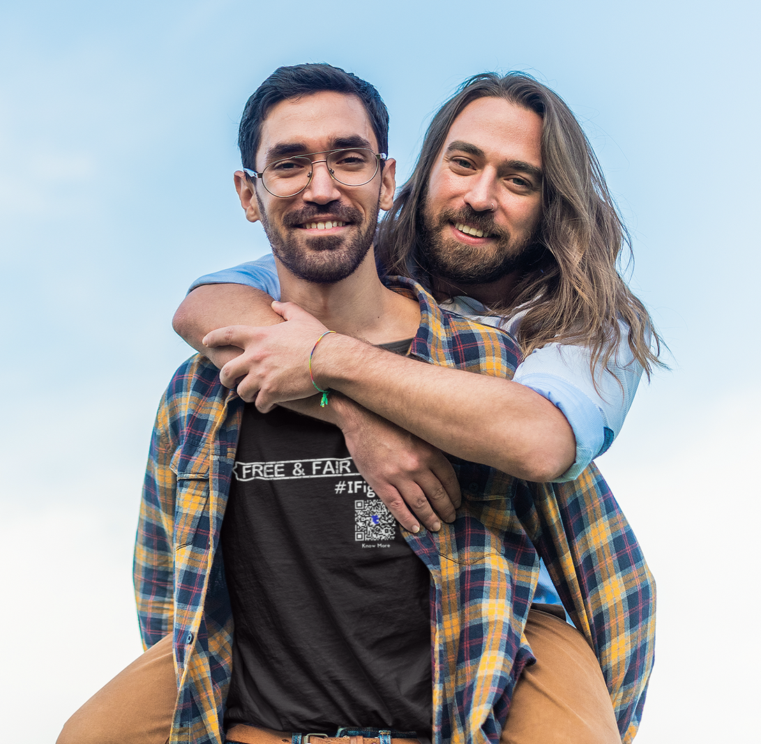 A male presenting person is giving his boyfriend a piggyback ride. He is wearing a black CLAIM It Tee™. The CLAIM is {FREE & FAIR VOTING} #IFightFor 