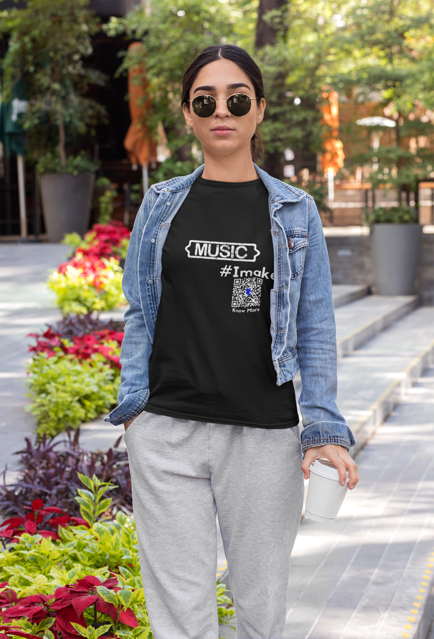 A female presenting person is walking outside in a city setting. They're in pants, denim jacket, & CLAIM It Tee™. The CLAIM™ reads {MUSIC} #Imake.